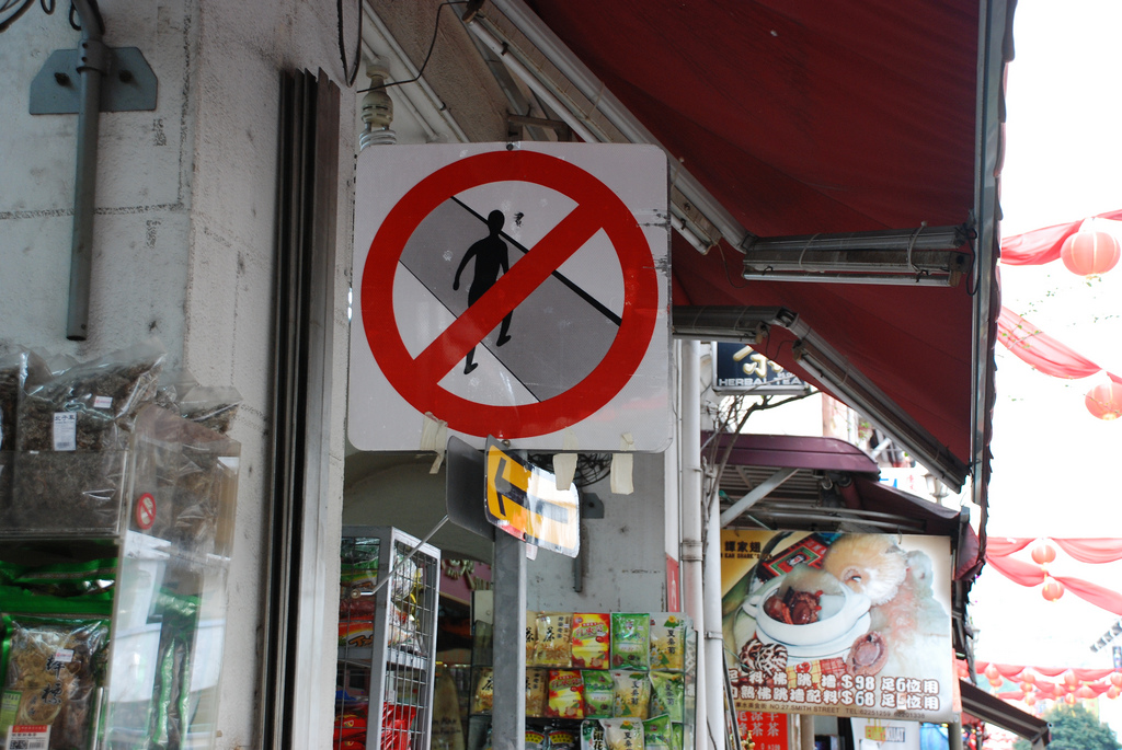 Placa informando que é proibido atravessar a rua fora da faixa em Singapura.