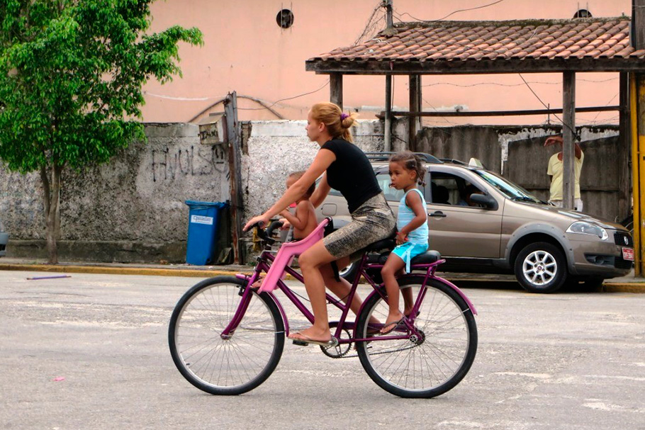 Crianças na bicicleta com cuidadora.